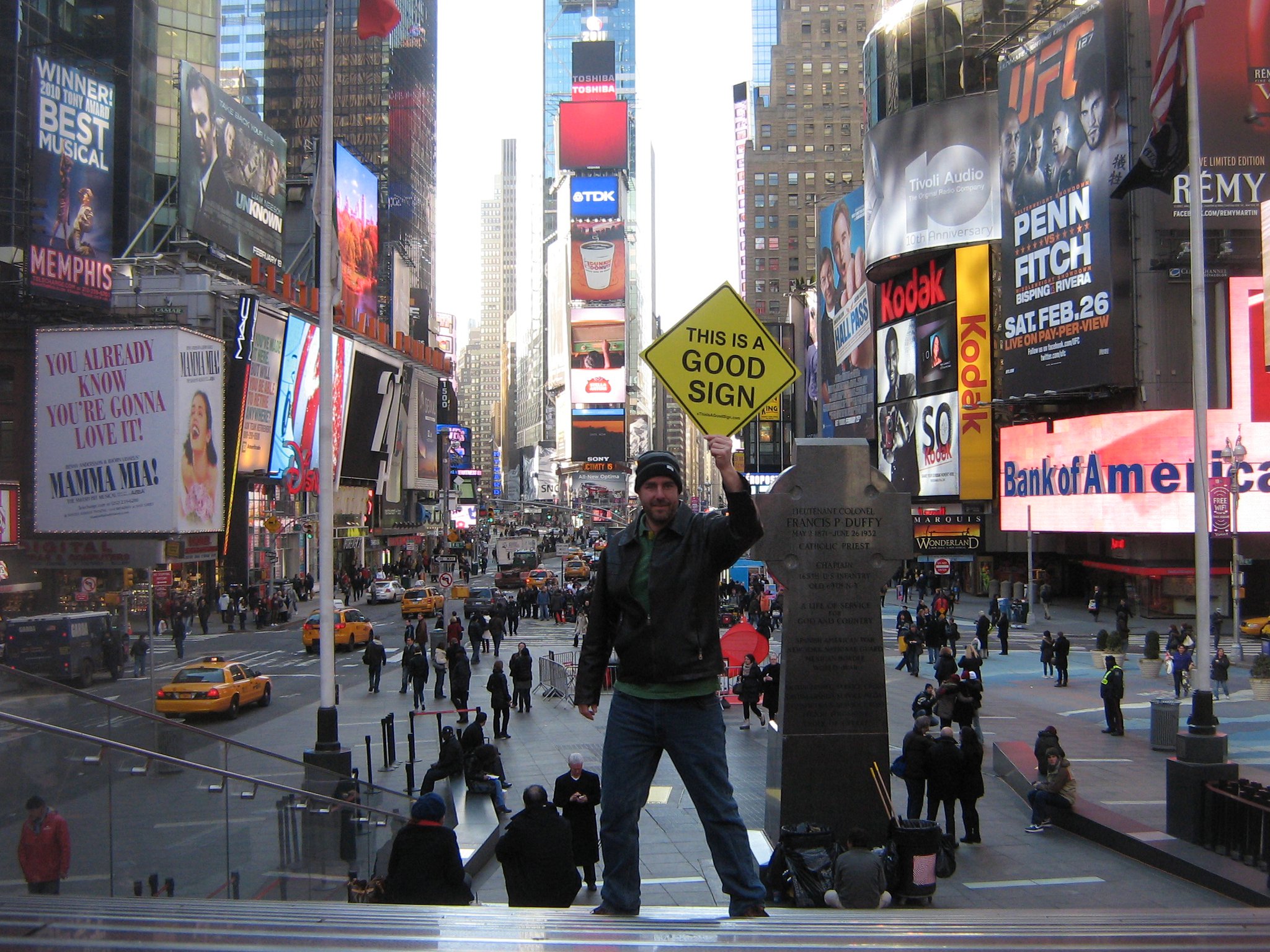 A person holding a Good Sign above the crowd in Times Square