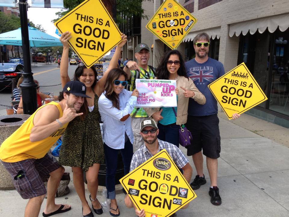 A community group posing together with several Good Signs